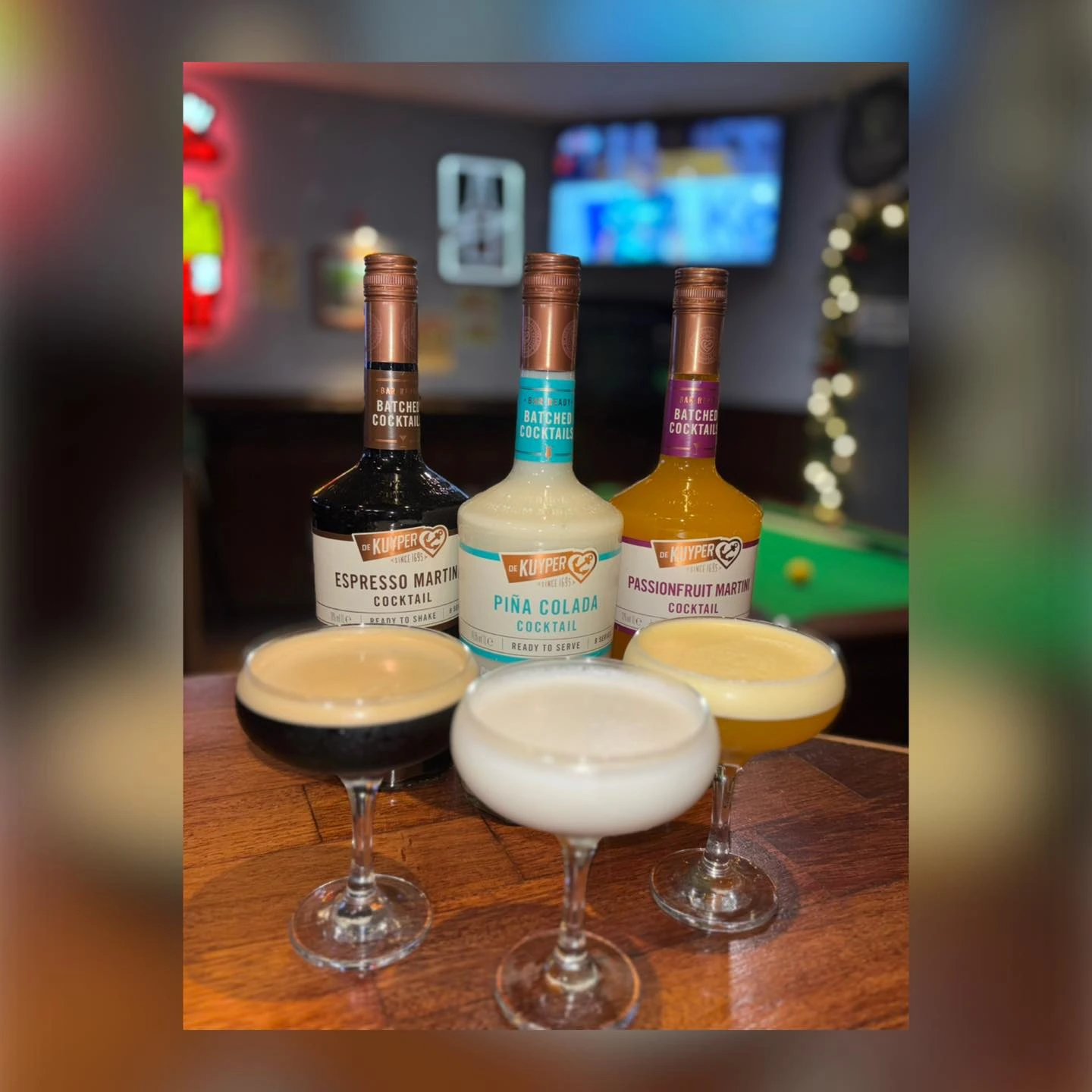 Flight of colourful mixed drinks on a wooden table at The Burgh Bar Dunoon