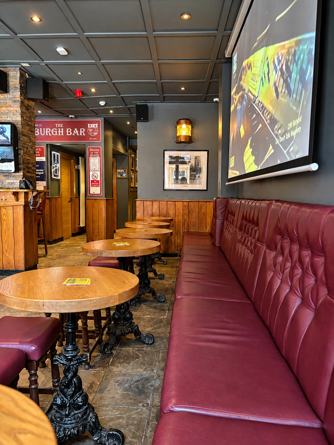 Red banquette seating and wooden tables inside The Burgh Bar Partick