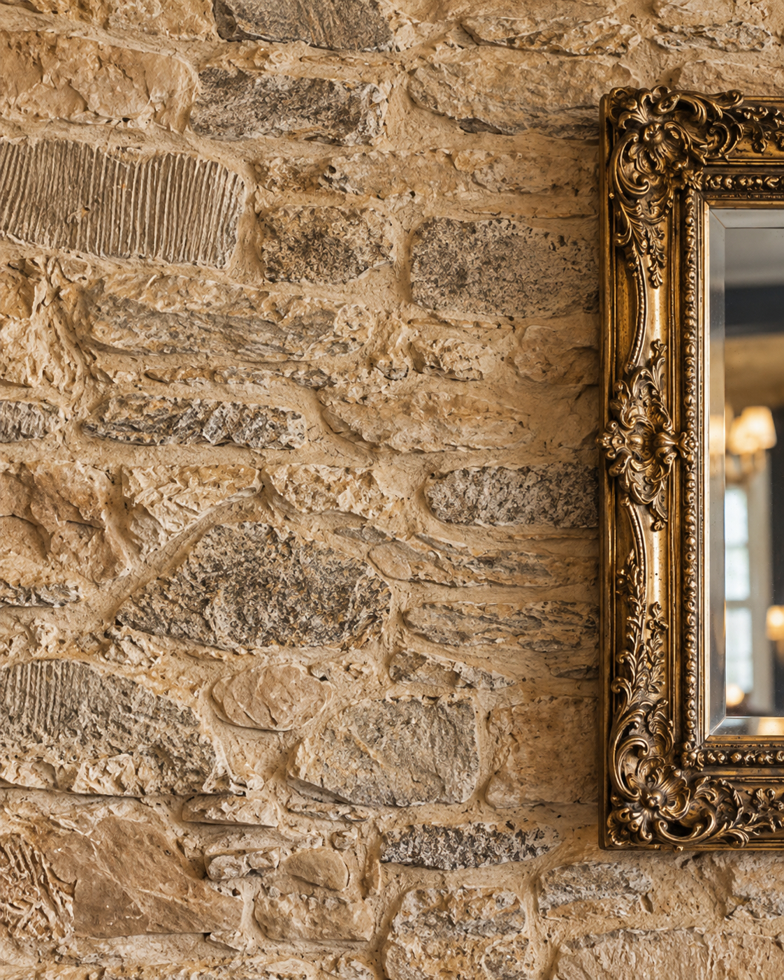 Ornate framed mirror against a stone wall at Milne’s in Dunoon