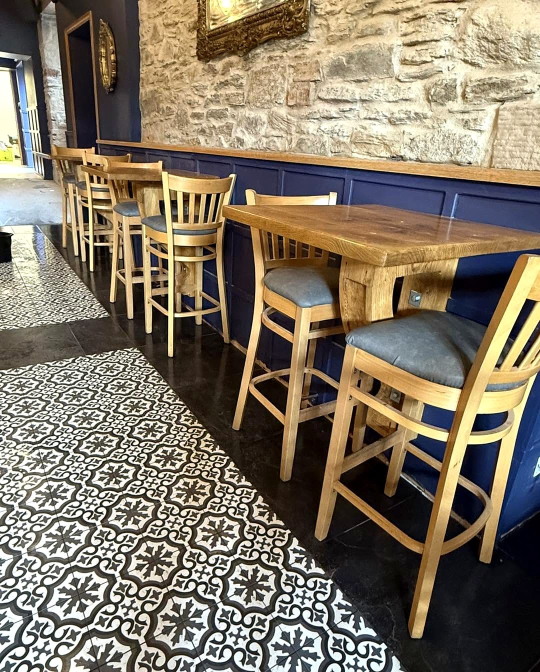 Wooden chairs and blue bench seating beside a stone wall at Milne’s